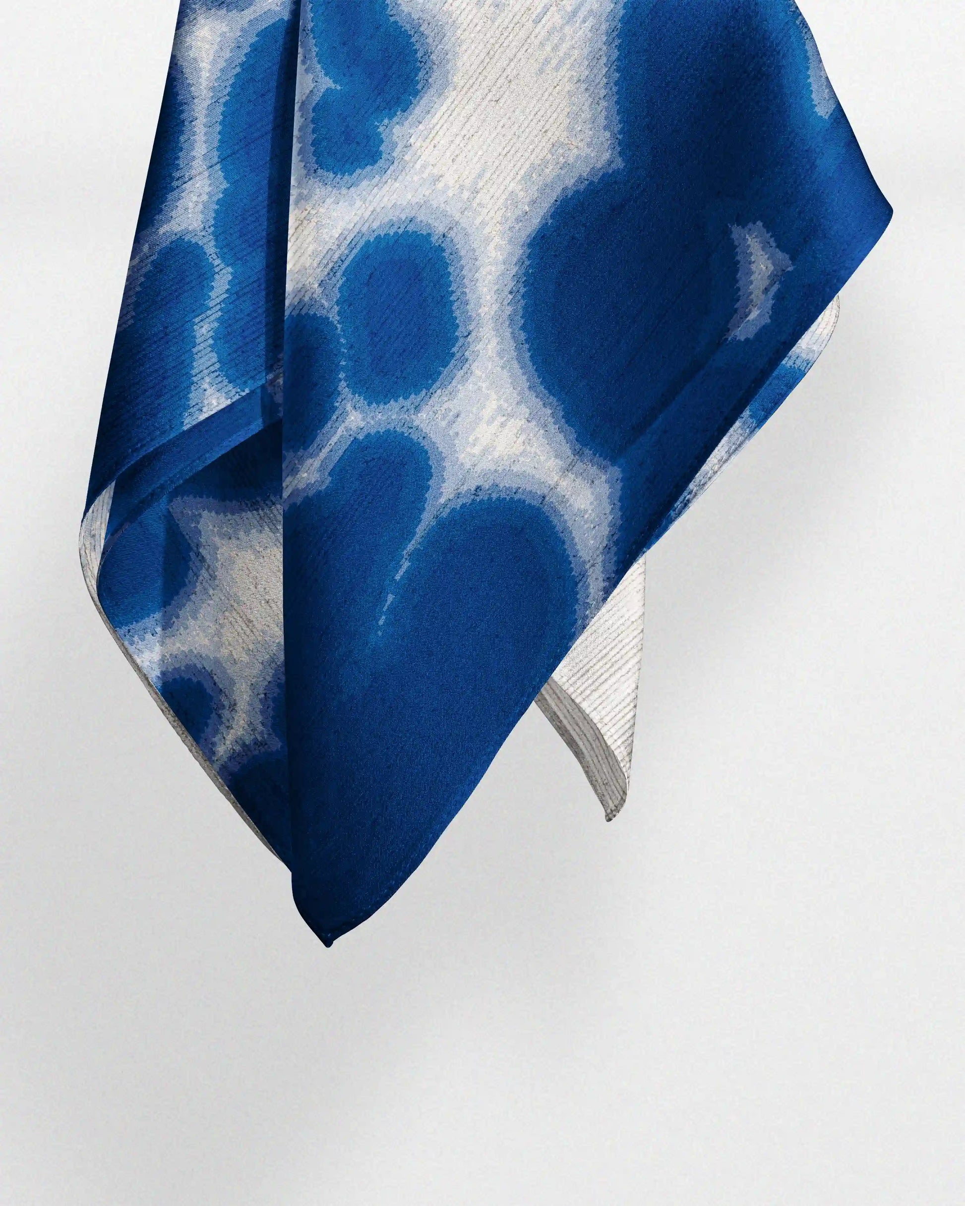 Klein Blue and off-white patterned silk handkerchief made with 100% mulberry silk, relax and naturally drop on a light beige background. An eclectic Y2K  fashionable  accessory for dopamine dressing.