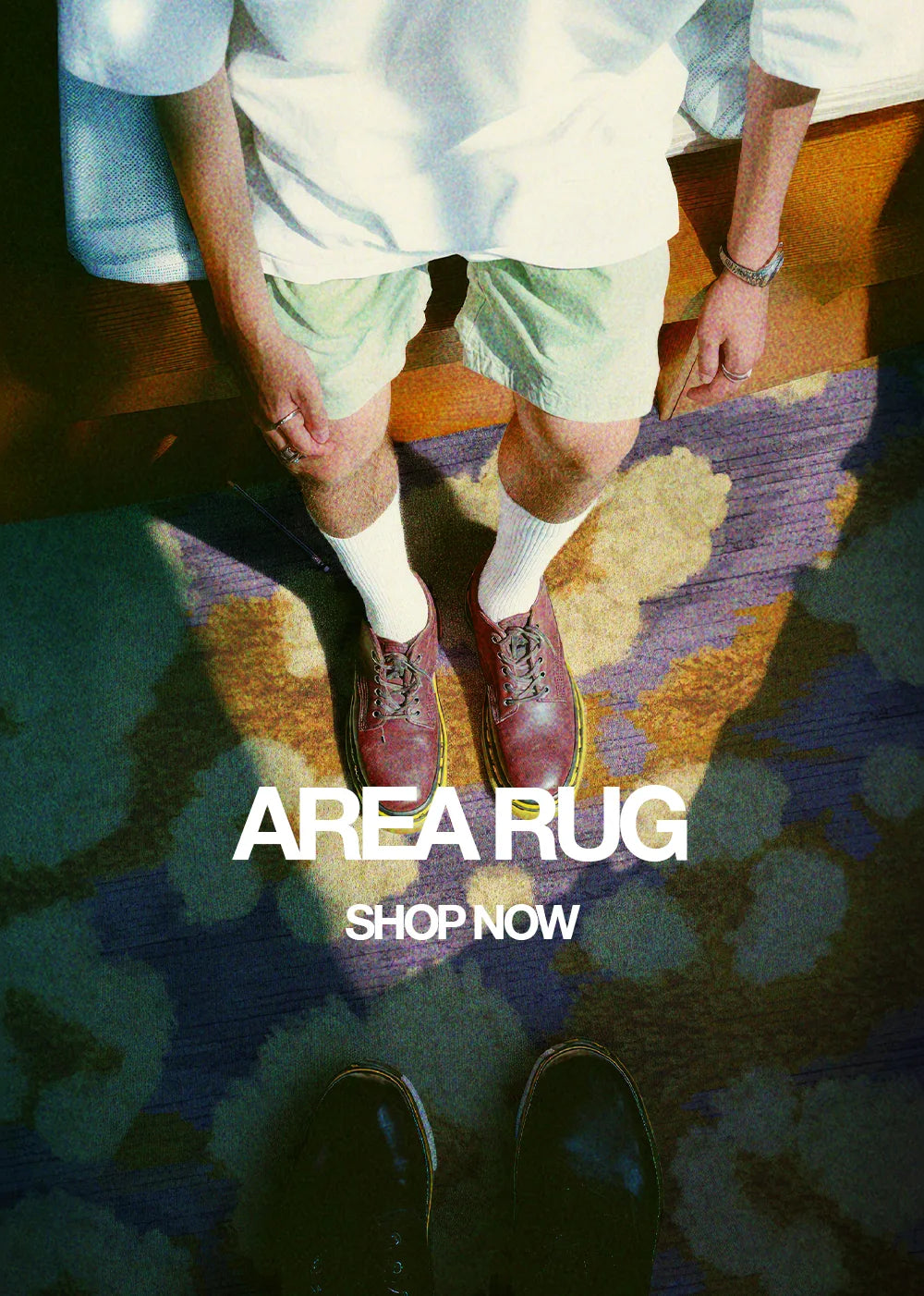 A banner for the rug collection displays two men standing on an eclectic area rug with shades of purple and yellow in a living room.