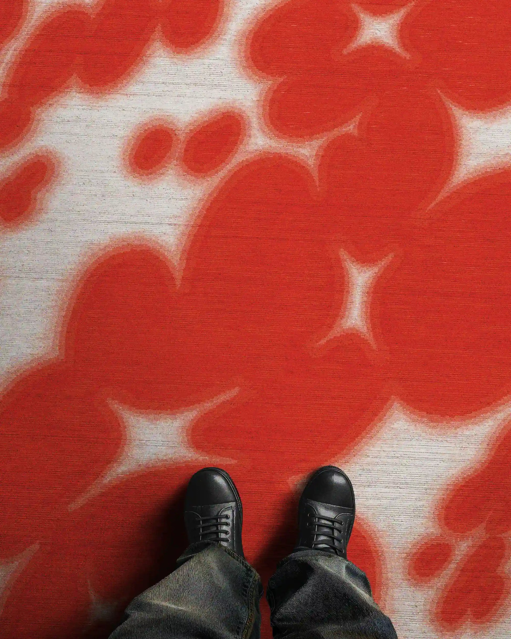 Man stands on an eclectic home decor, the dopamine colorful red and white floral cowhide aura area rug, with abstract resembling cowhide animal print printed on a faux wool, low pile area rug, size 8x10 ft.