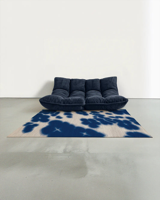 Cowhide floral Aura area rug 5x7 ft, in Klein blue and off white hues, artfully placed in a contemporary studio with a dark navy blue togo sofa.