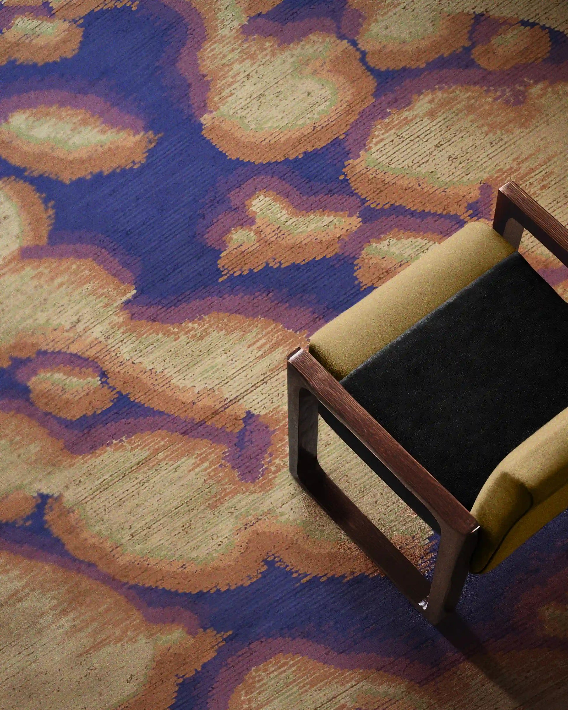 Fall eclectic purplish blue and creamy yellow abstract camouflage area rug with slight touch of pale purple placed underneath a yellow wood armchair in the modern apartment. Dopamine home decor for maximalist home.