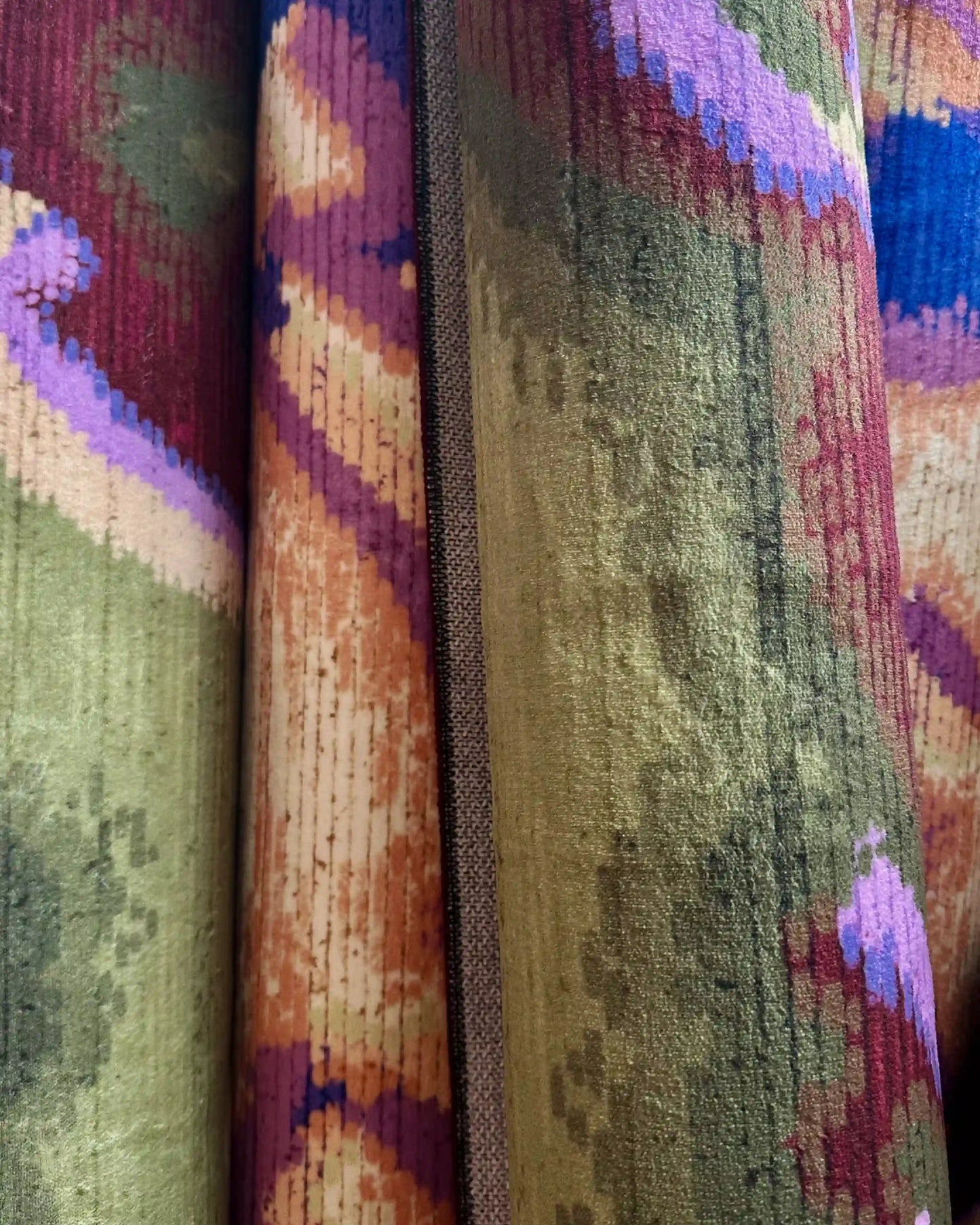Close-up texture showing 2 color variants of the colorful and vibrant camouflage area rug with a 3mm pile height: purplish blue and creamy yellow, burgundy and olive green.