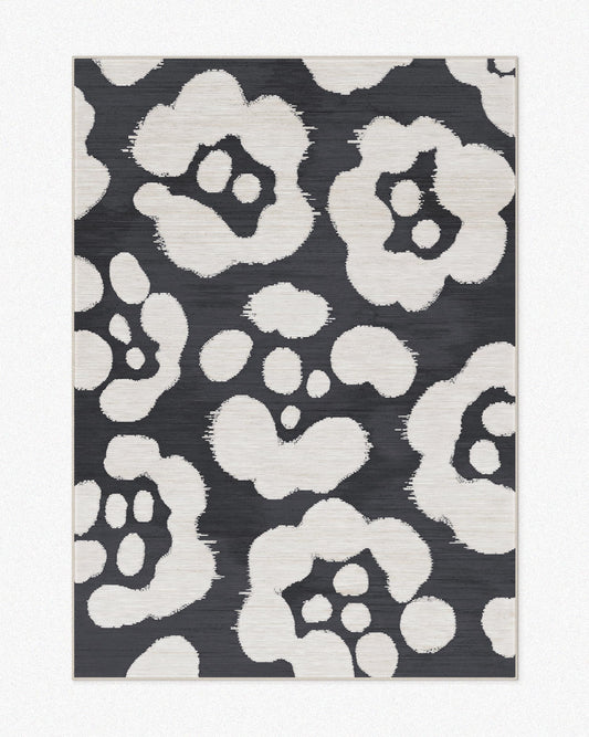 Floral area rug 5x7 with floral patterns and black and off white hues set against a light beige background, highlighting its mid century modern aesthetic.