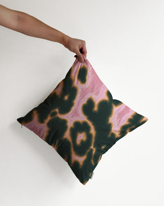 A hand holding a bold abstract cowhide and floral cushion cover in pink and dark green, against a minimalist beige background, perfect for eclectic dopamine decor in a maximalist apartment.