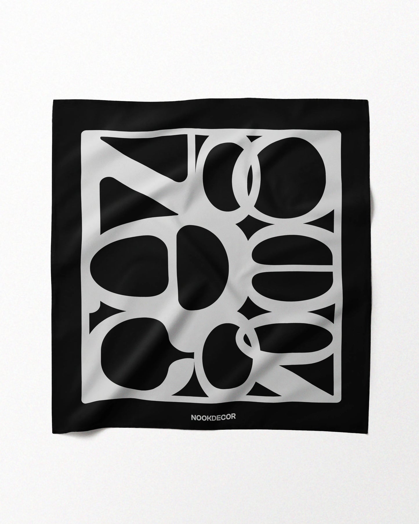 A classic black and white handkerchief features NOOKDECOR’s brand logo design and is made with 100% mulberry silk, laid flat on a beige background, showcasing its eclectic style.