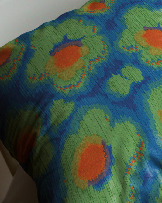Extreme close-up of abstract leopard and floral print cushion cover, showcasing high-contrast colors of green, blue and orange and colorful leopard pattern details.