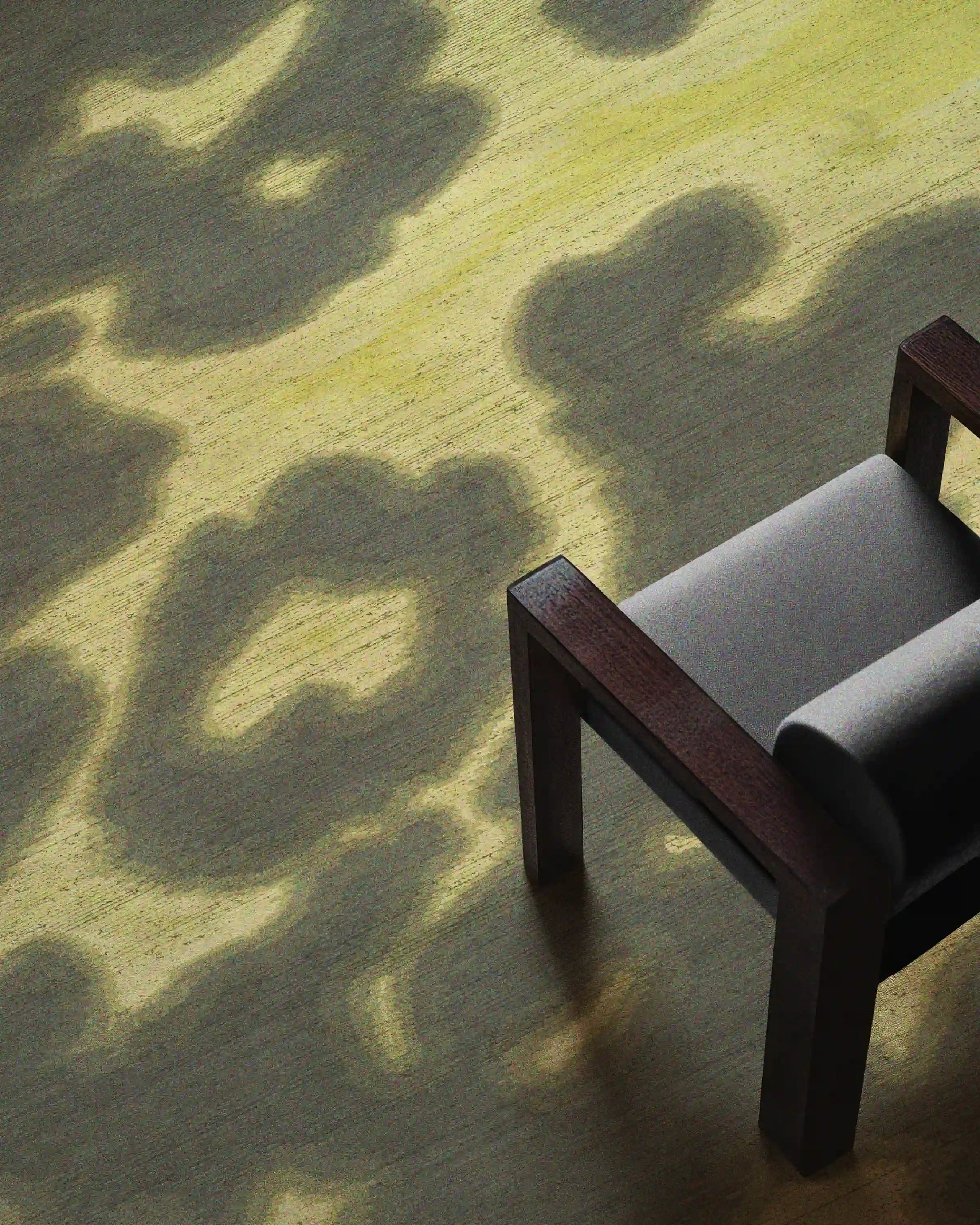 Floral cowhide rug in grey khaki and light yellow aura area rug placed underneath a light grey wood armchair in the living room.