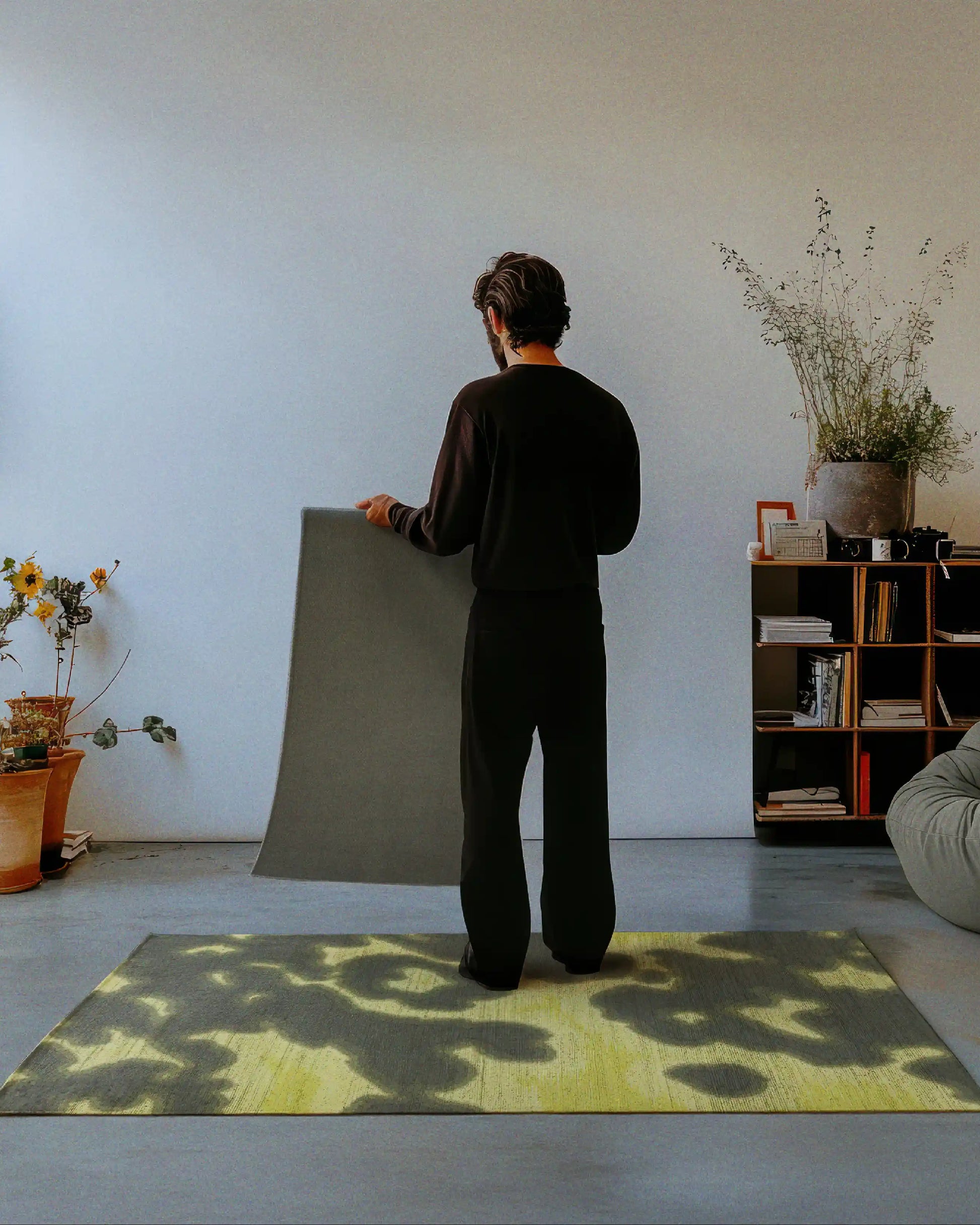 Person holding and showing the back of the rug with a slip-resistant backing showcase in a living room, highlighting a demonstration of the grey khaki and yellow hues animal print, abstract cowhide pattern printed on the faux wool low pile area rug for the maximalist eclectic home.