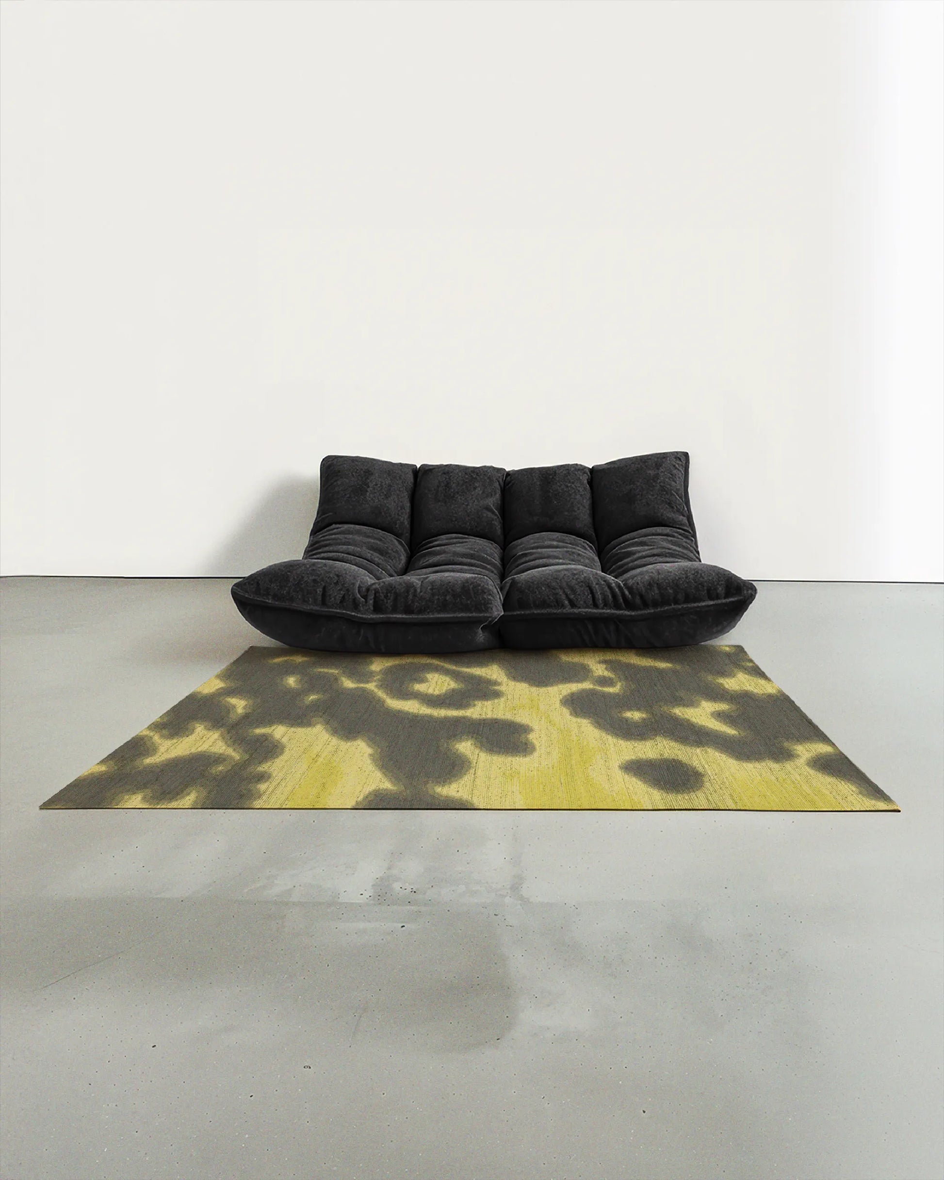 Aura area rug 5x7 ft, with a delicate abstract cowhide floral pattern in grey khaki and light yellow, artfully placed in a contemporary studio with a dark grey togo sofa.