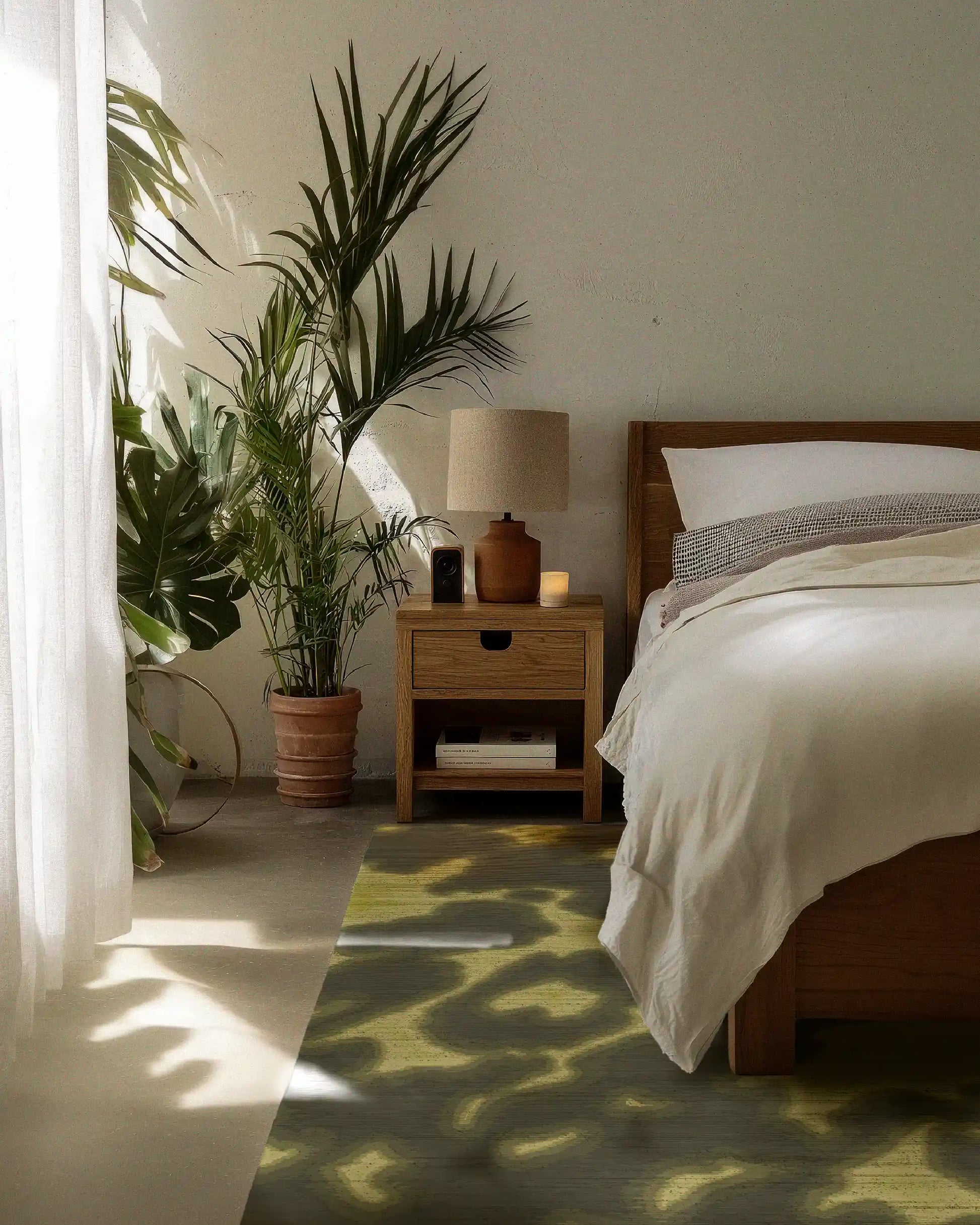A 5x7 ft abstract cowhide area rug in grey khaki, and light yellow hues is placed underneath a wood-framed bed, with minimalist home decor and large house plants in the bedroom.