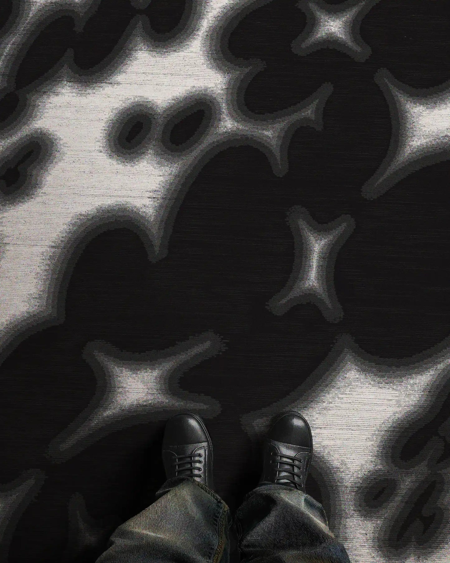 A man stands in an eclectic home decor setting, featuring the bold black and off white floral cowhide area rug, 8x10 ft, in a studio. Perfect bold decoration item for Scandinavian mid century modern home.