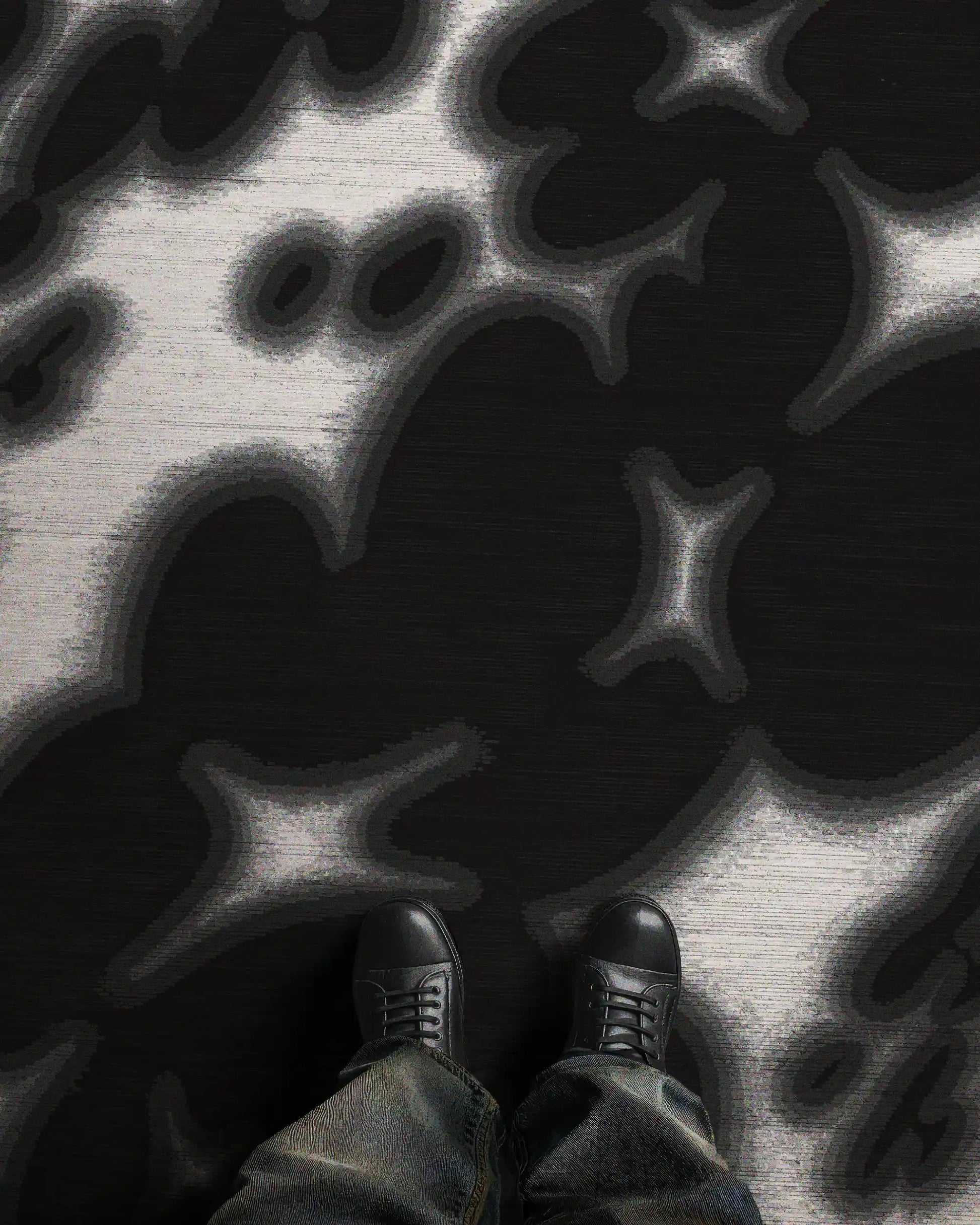 A man stands in an eclectic home decor setting, featuring the bold black and off white floral cowhide area rug, 8x10 ft, in a studio. Perfect bold decoration item for Scandinavian mid century modern home.