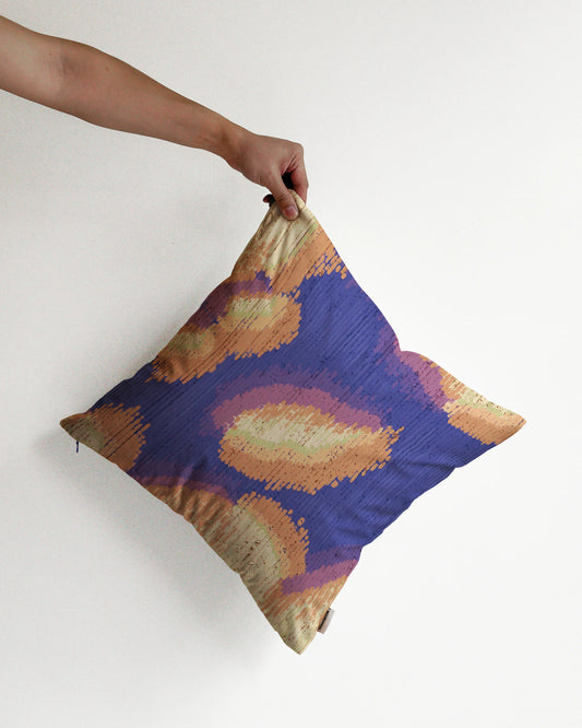 A hand holding a fall vibe, abstract camouflage cushion cover in creamy beige yellow, purplish blue, peach hues, against a minimalist beige background, perfect for eclectic dopamine decor in a modern apartment.