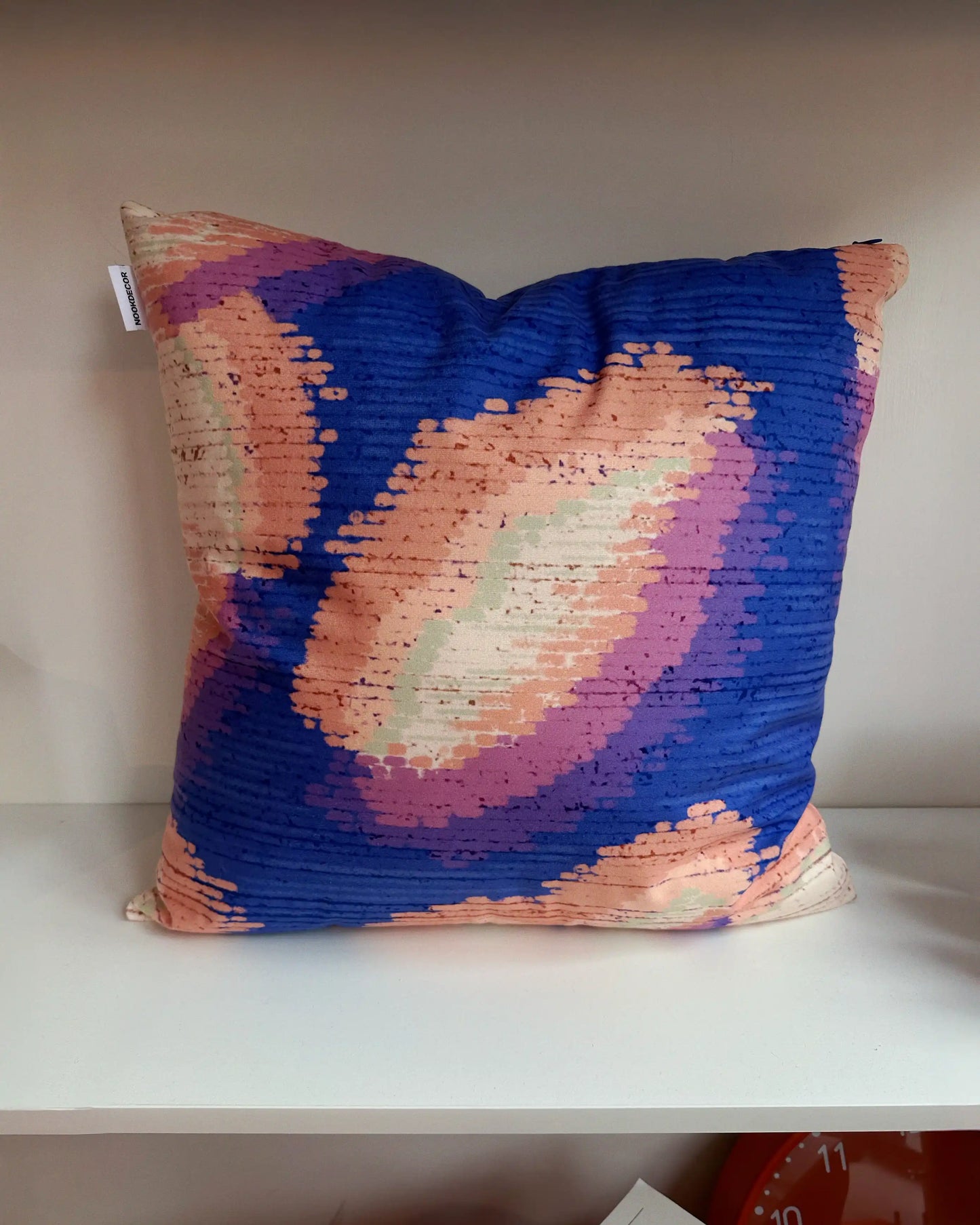 Abstract camouflage cushion covers in purplish blue and light green yellow hues, layered on shelf in modern living room, showing bold pattern mixing with solid throw pillows for 2026 eclectic interior design.