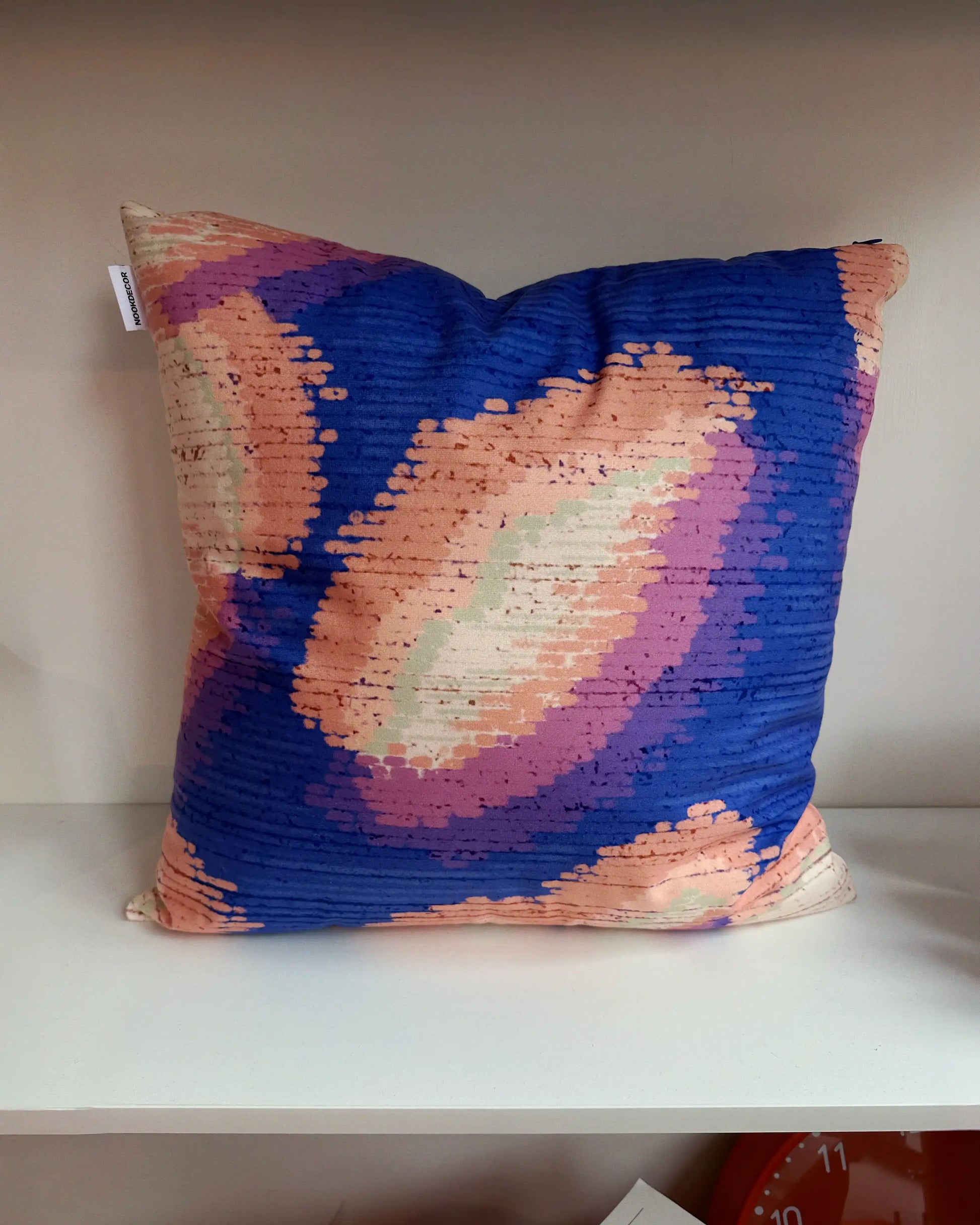 Abstract camouflage cushion covers in purplish blue and light green yellow hues, layered on shelf in modern living room, showing bold pattern mixing with solid throw pillows for 2026 eclectic interior design.