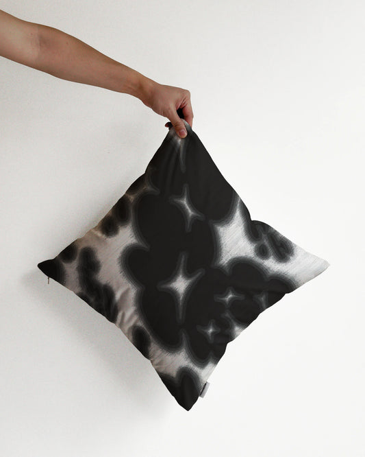 A hand holding a bold, abstract floral and cowhide cushion cover in black and off white hues, against a minimalist beige background, perfect for eclectic dopamine decor in a modern apartment.