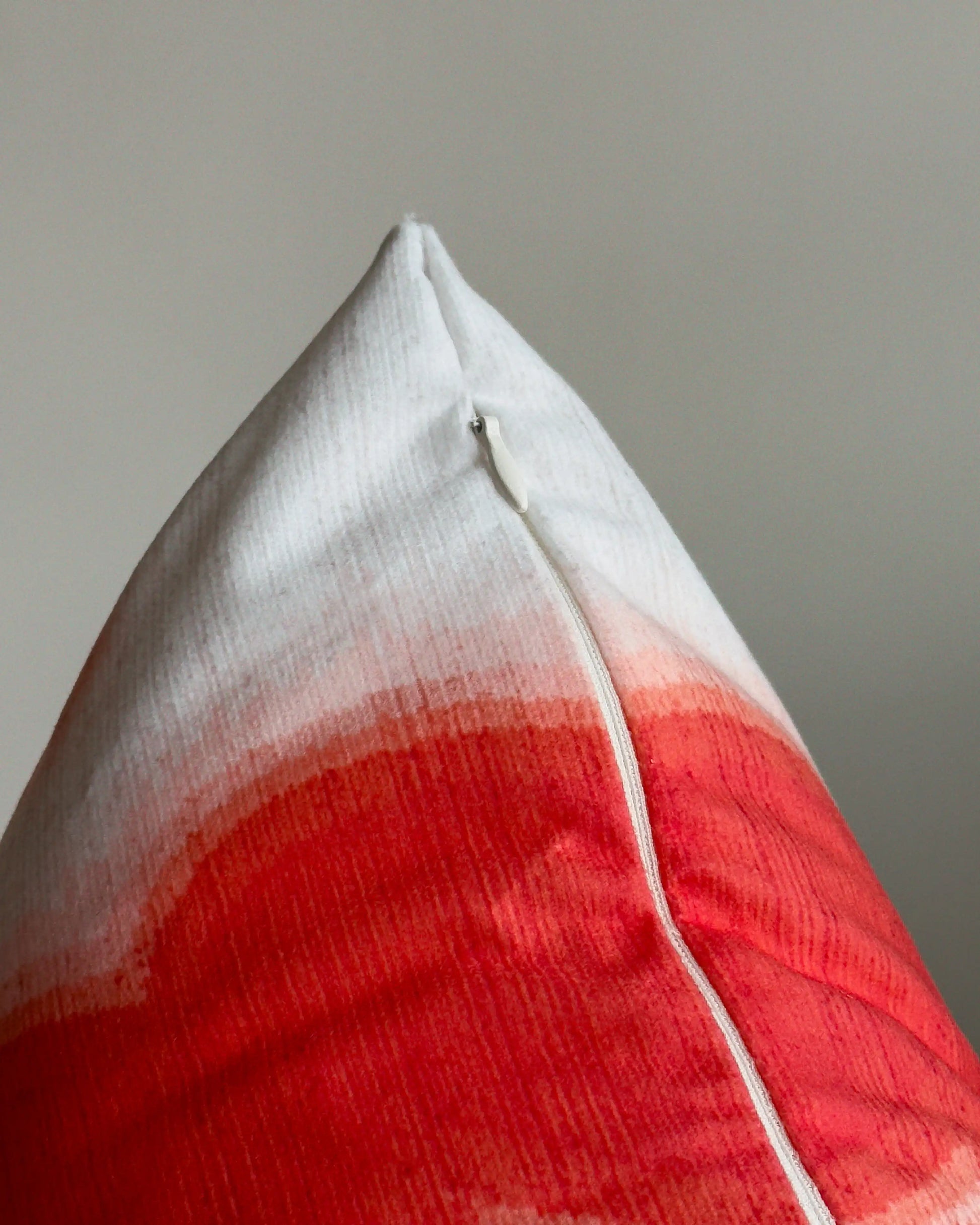 Close-up of hidden zipper closure in cream white on red and off white abstract floral cowhide cushion cover, showing easy insertion and premium construction details.