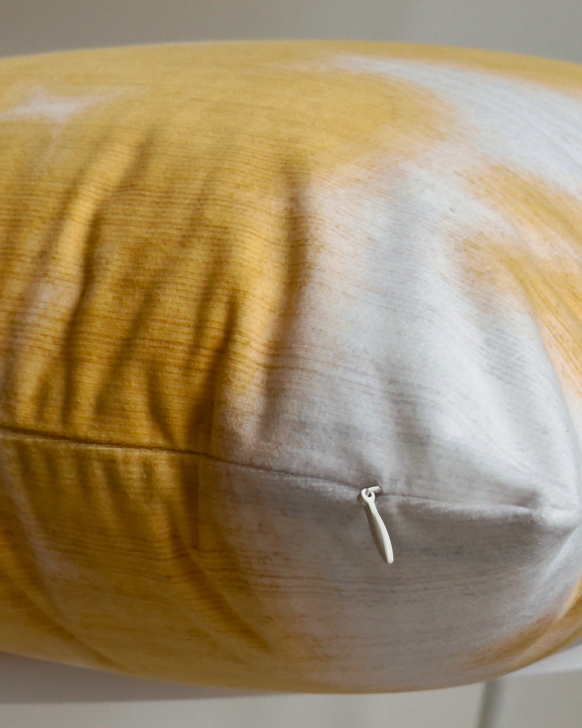 Close-up of hidden zipper closure in cream white on yellow and off white abstract floral cowhide cushion cover, showing easy insertion and premium construction details.