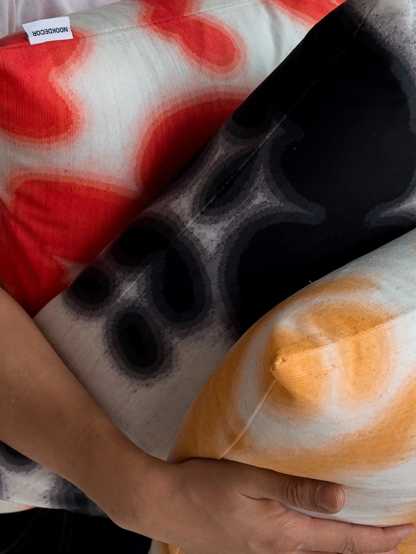 Hand holding a set of three coordinating abstract cowhide floral cushion covers, showing mix of abstract cowhide and floral patterns for bold dopamine sofa styling.
