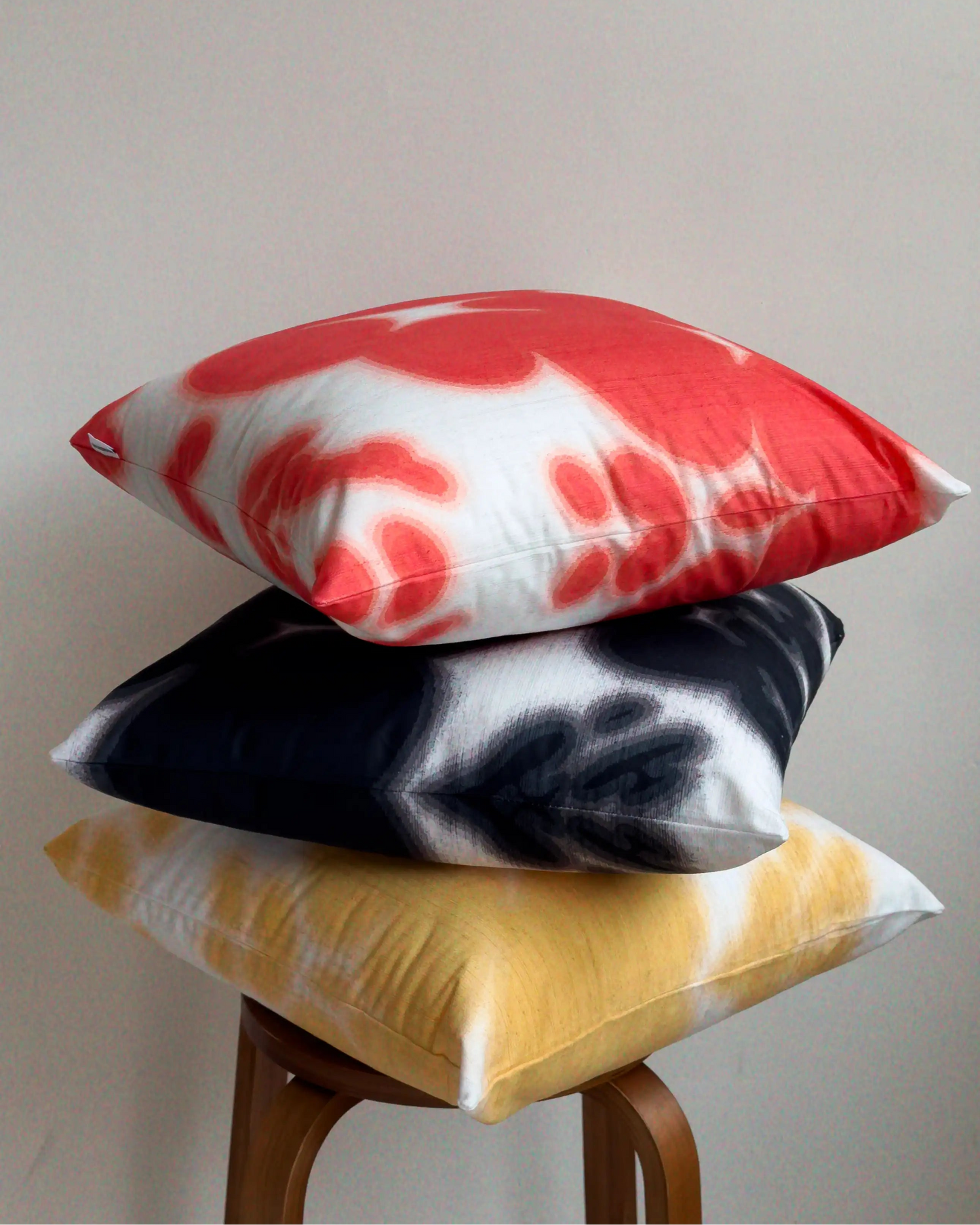A set of three coordinating abstract cowhide floral cushion covers, showing mix of abstract cowhide and floral patterns for bold dopamine sofa styling in red, yellow, black and white.