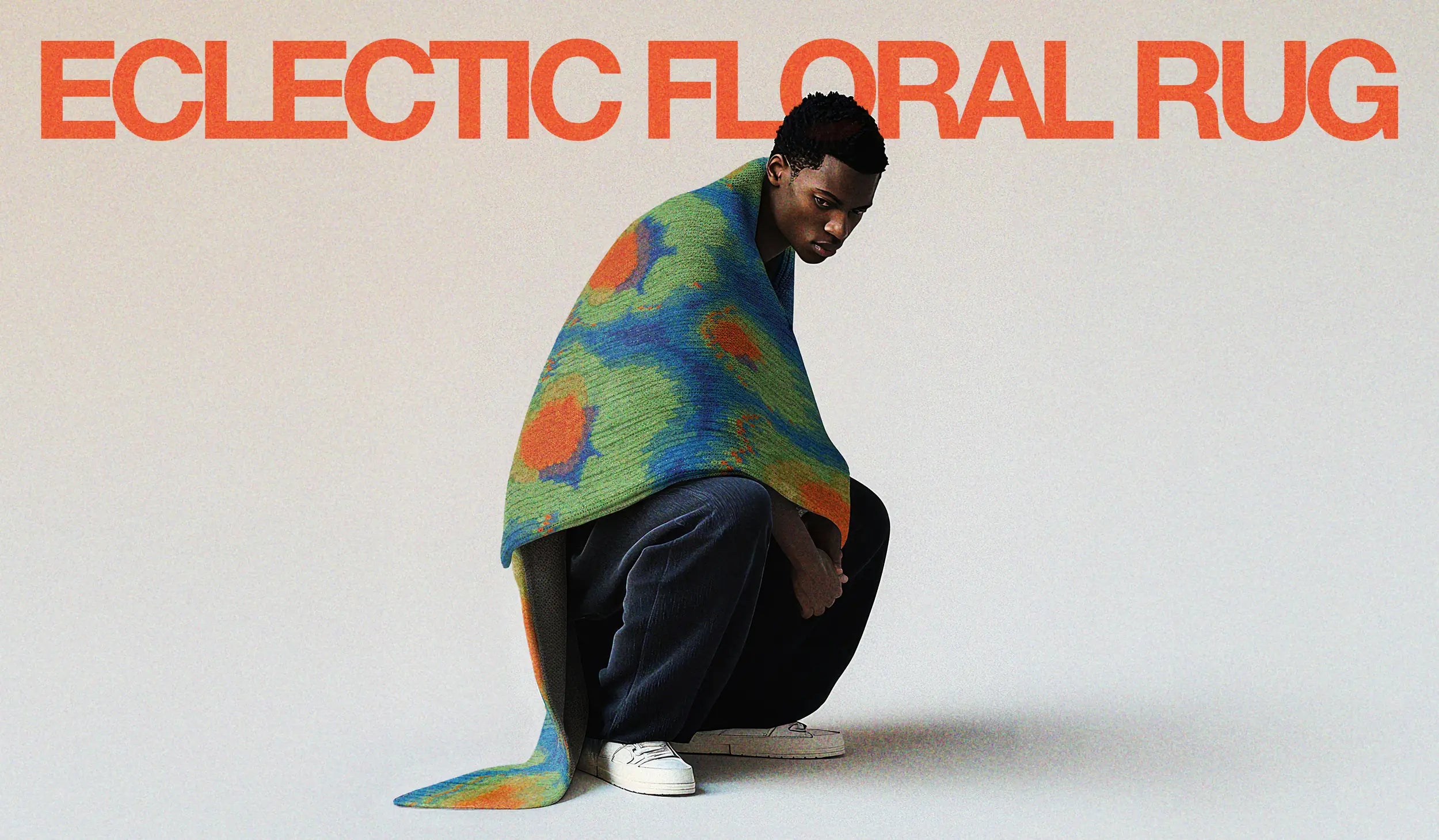 Homepage hero image of A man poses with an eclectic area rug, with vivid floral rug in bright green, Klein blue, and orange shades.