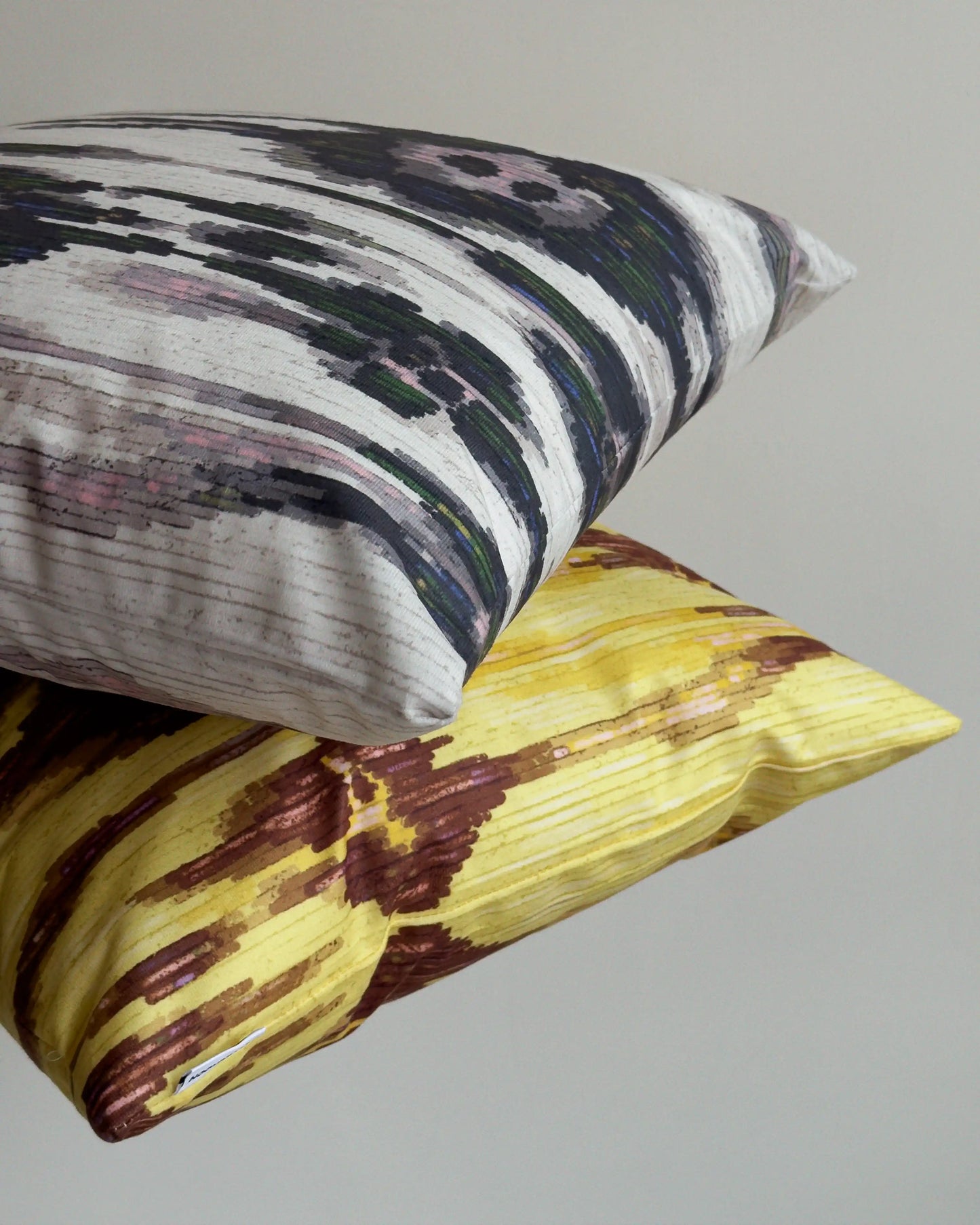 Set of two coordinating abstract cushion covers held against beige white wall, showing mix of floral leopard patterns for bold sofa styling. Perfect for eclectic dopamine decor in a modern living room.