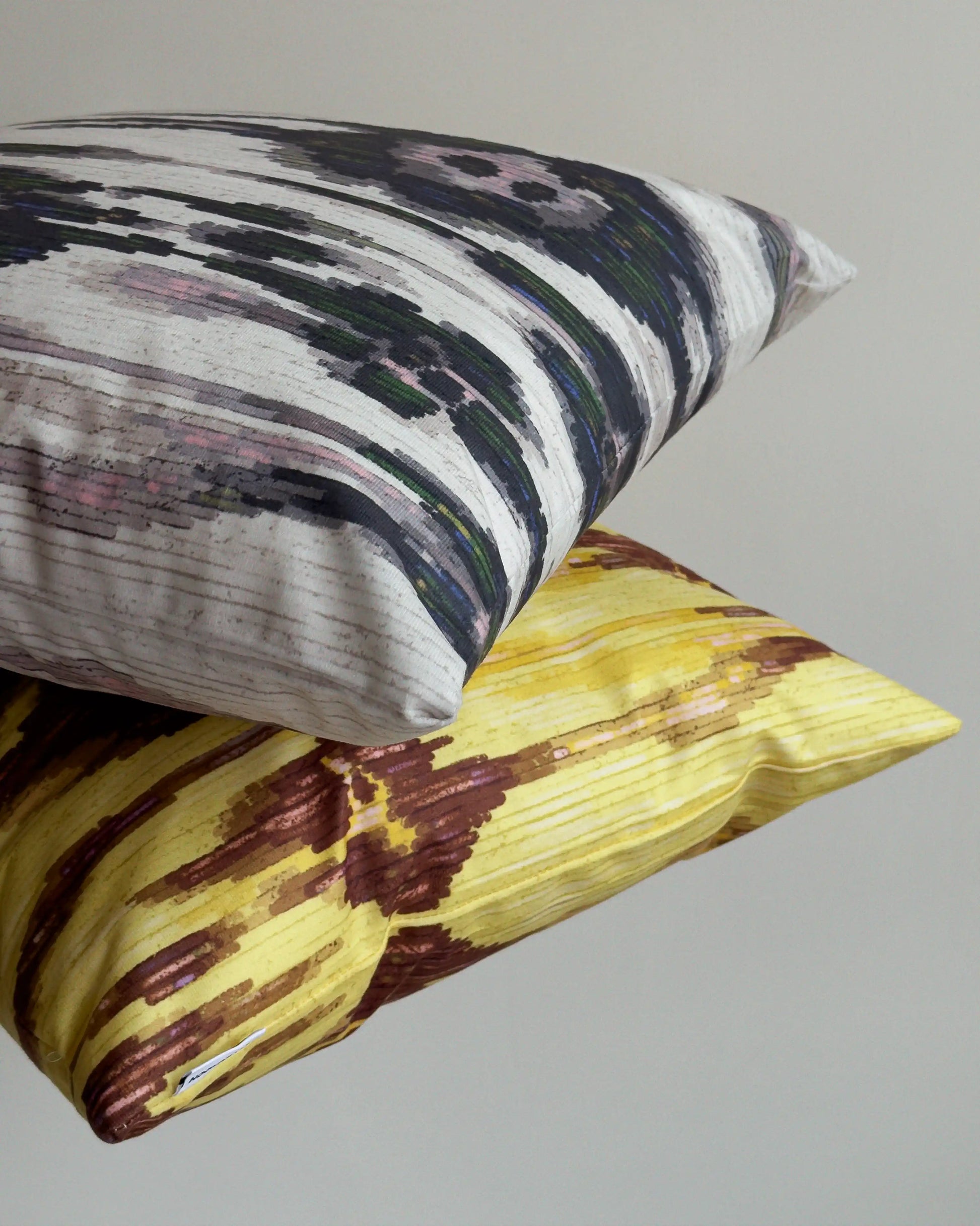 Set of two coordinating abstract cushion covers held against beige white wall, showing mix of floral leopard patterns for bold sofa styling. Perfect for eclectic dopamine decor in a modern living room.