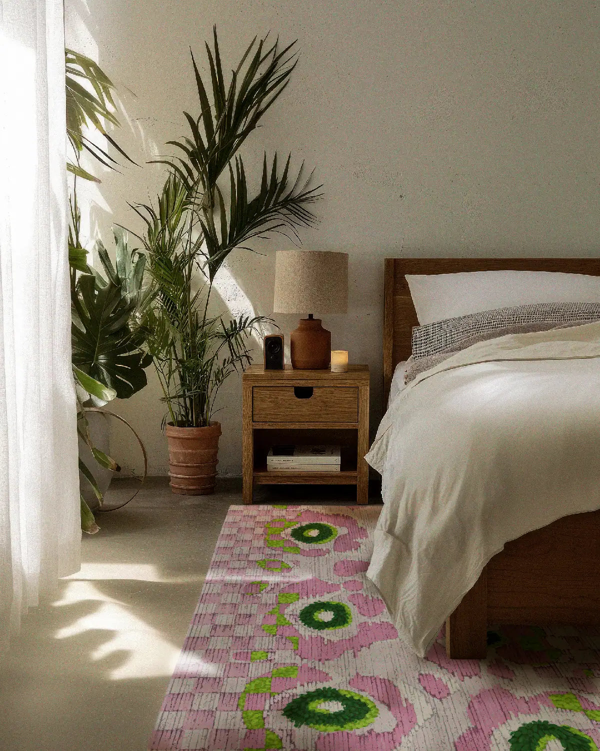 Green checkered rug with pink leopard  floral design placed in contemporary bedroom with wood framed bed and house plant.