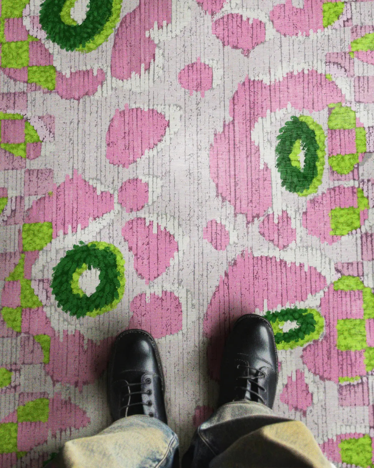 A man stands on the pink and green checkered rug 5x7 with pink floral patterns in a contemporary living room.