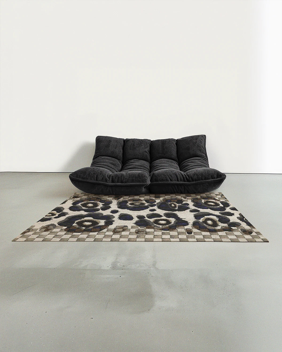 Black and white checkered area rug with floral pattern, placed in a contemporary studio with dark grey togo sofa accent.