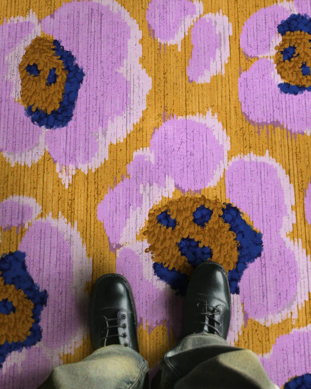 A man wearing trendy and stylish faded jeans and black leather shoes stands on the modern eclectic home decor floral area rug in abstract purple and yellow leopard patterns design.