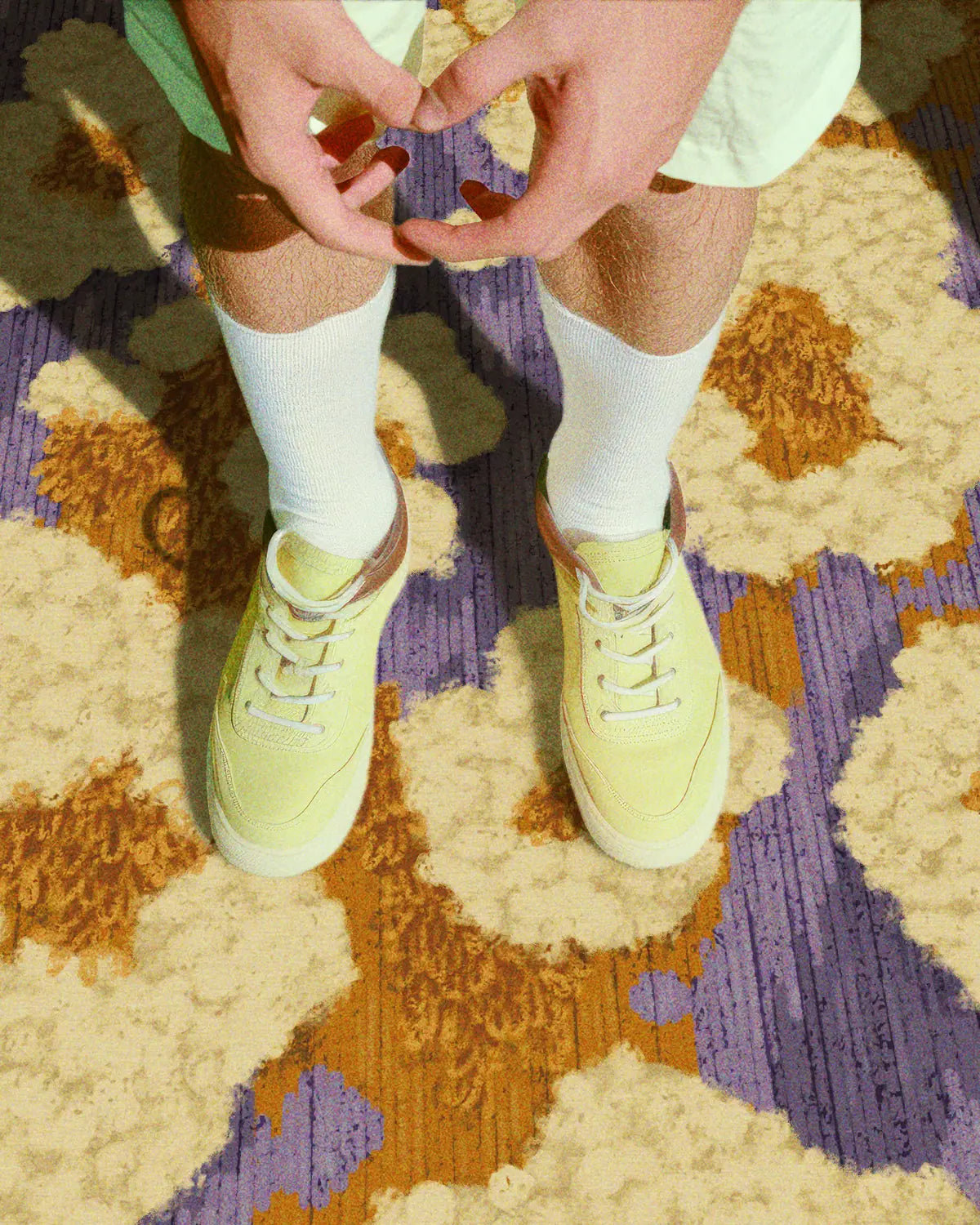 A man in yellow sneakers stands on the colorful area rug 8x10, which features cute, abstract popcorn patterns in purple and yellow. Dopamine home decor for a maximalist apartment.