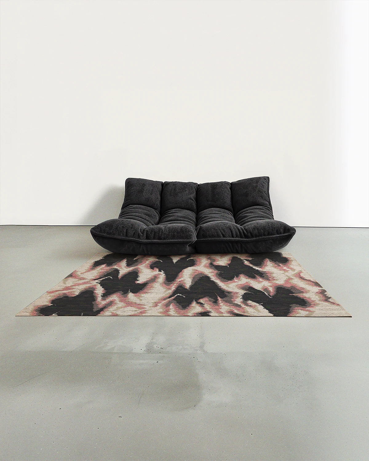 The contemporary area rug features pink and grey aura patterns placed in a modern studio with a grey Togo sofa.