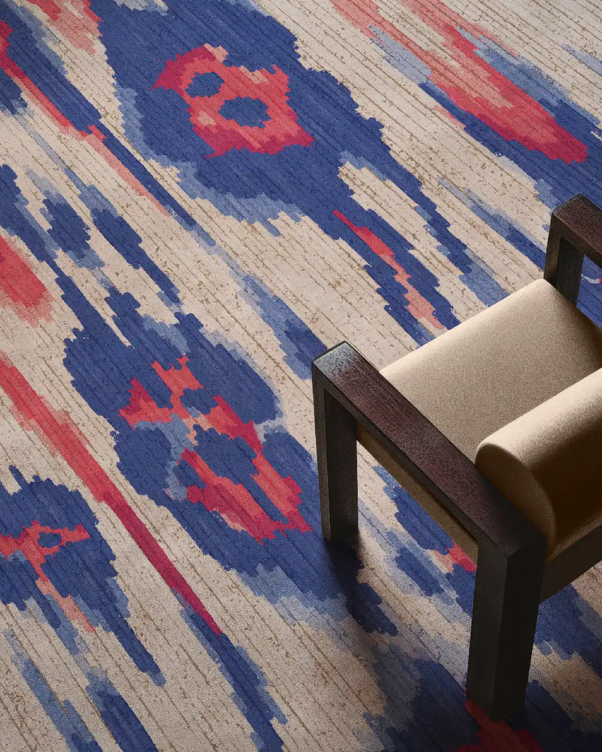 Maximalist colorful abstract rug with coral, blue and beige hues and leopard patterns with a beige wooden chair in a modern home.