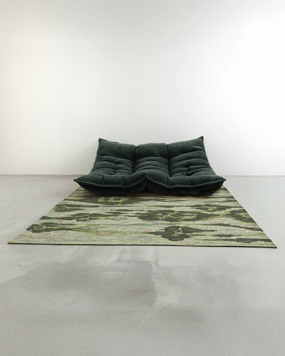 Abstract leopard floral rug 5x7 in sage green hues with an aura rug design was placed in a contemporary studio with a dark green sofa accent.