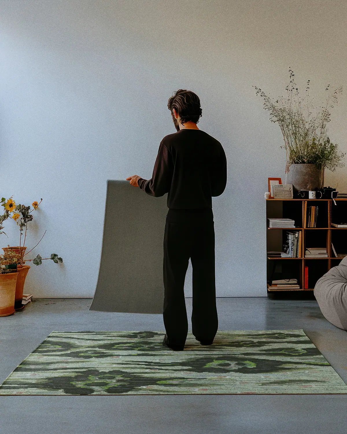 A man dressed in all black stands on an abstract animal print, leopard floral checkered rug 4x6, showing the nonskid rug backing of a 2x3 rug in a modern studio.