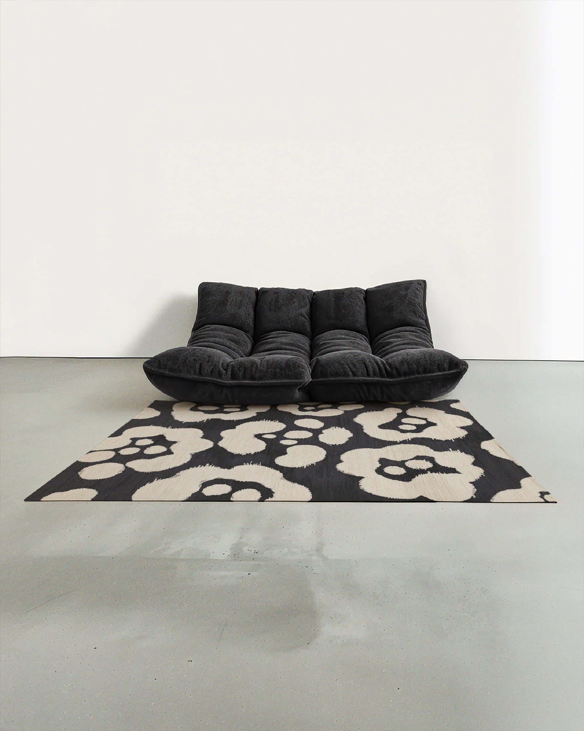 Area rug 5x7 with a cute floral pattern in black and off white, placed in a Scandinavian studio with a black togo sofa.