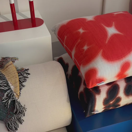 Product video of red white and brown white floral cushion, throw pillow in eclectic studio. Dopamine home decor for maximalist apartment.